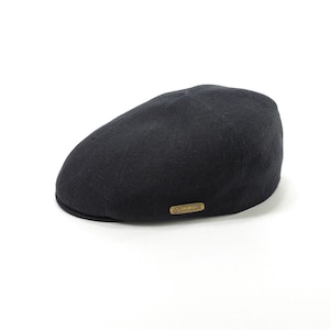 May include: A black, flat cap with a rounded crown and a small, stiff brim. The cap has a textured appearance and a small, rectangular, gold-colored label on the side. The hat is set against a white background.