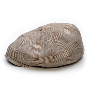 Pu&ograve; includere: Un berretto newsboy a quadri marrone e beige. Il berretto presenta un classico design a otto pannelli con un bottone sulla parte superiore e una visiera corta e curva. Il motivo a quadri include sfumature di marrone, beige e un tocco di blu.