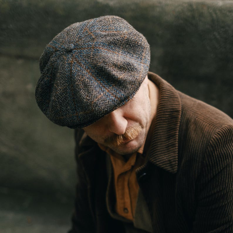 Puede incluir: Un hombre con una chaqueta de pana marr&oacute;n y una gorra de tweed de estilo newsboy con un patr&oacute;n azul y marr&oacute;n.