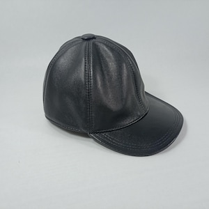 May include: A black leather baseball cap with a curved brim. The cap has a stitched seam down the center of the crown.