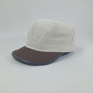 May include: A white canvas baseball cap with a brown leather brim. The cap has a stitched band around the crown.