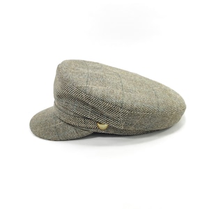 Puede incluir: Gorra de estilo newsboy de tweed en tonos grises y marrones, con una pequeña visera redondeada y un botón decorativo. La gorra presenta un aspecto clásico y texturizado.