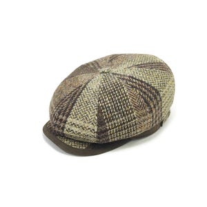 May include: A brown and tan tweed newsboy cap with a dark brown brim. The cap has a classic plaid pattern and is made of a textured fabric. This hat is a stylish accessory.