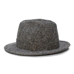 Peut inclure: Un chapeau fedora en tweed gris avec un bandeau marron foncé. Le chapeau a une forme classique et structurée avec un bord légèrement incurvé. Le tissu en tweed présente un motif moucheté avec des mouchetures marron et blanches.