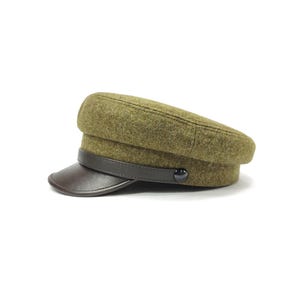 Op de afbeelding: Een olijfgroene wollen hoed met een donkerbruin leren vizier en band. De hoed heeft een ronde kroon en een kleine, donkere knoop aan de zijkant. Deze klassieke hoed is een modieus accessoire.