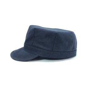 May include: A navy blue military-style cap with a short brim. The cap has a structured crown and a band around the base. The hat is made of a solid, dark blue fabric.