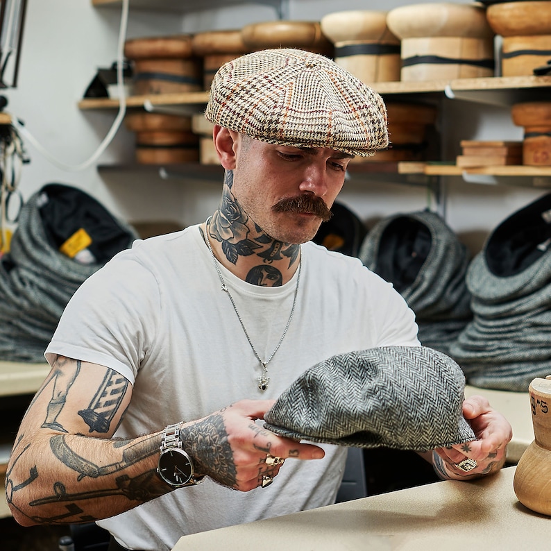May include: A gray and brown tweed newsboy cap with a checkered pattern.