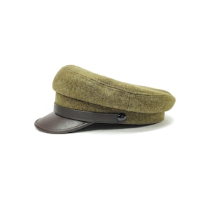 Op de afbeelding: Olijfgroene pet in militaire stijl met een donkerbruin leren vizier en band. De pet heeft een afgeronde kroon en een kleine, zwarte knoop. De hoed is gemaakt van een textuurstof.
