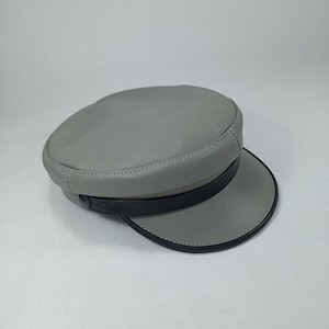 May include: A grey leather cap with a black band around the crown. The cap has a slightly curved brim.