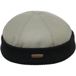 May include: A grey leather beanie with a black knit band. The beanie has a small brass tag with the word "Stenkoulska" on it.