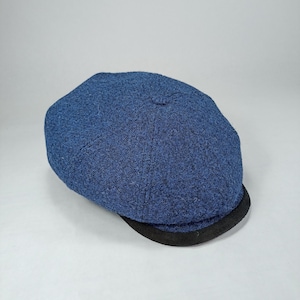 May include: A blue wool newsboy cap with a black brim.