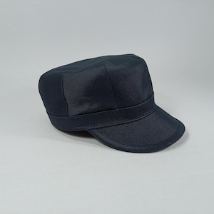 May include: A dark blue, flat-brimmed cap with a short, straight bill. The cap has a single, wide band around the crown.