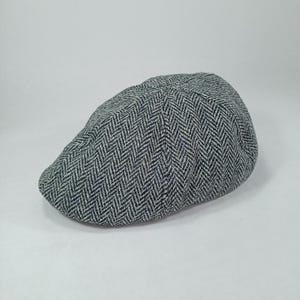 Peut inclure: Une casquette de newsboy à motif en chevrons gris et noir.