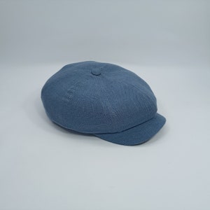 May include: A light blue linen newsboy cap with a slightly rounded crown and a short brim.