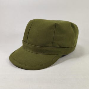 May include: Olive green military-style cap with a short brim. The cap has a structured crown and a band around the base. The fabric appears to be a durable, solid-colored material. This hat is a classic accessory.