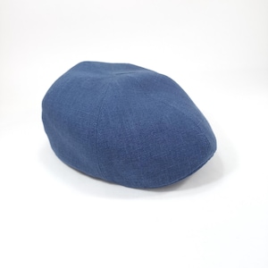 Peut inclure: Casquette de style gavroche bleu marine, fabriquée dans un tissu texturé. Le chapeau a un design classique avec une couronne arrondie et une petite visière rigide. Le chapeau est posé sur un fond blanc.