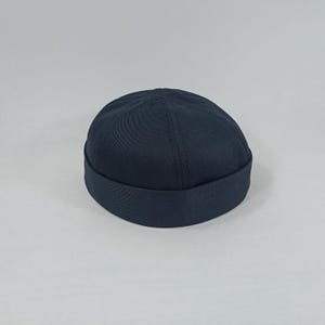 May include: A dark blue cotton beanie with a wide brim.