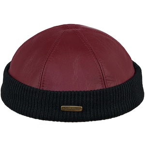 May include: A burgundy leather beanie with a black knit brim and a small gold label that reads "Sterskouske".