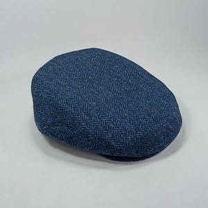 May include: A blue tweed flat cap with a herringbone pattern.