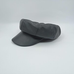 May include: A black leather newsboy cap with a rounded crown and a flat brim.
