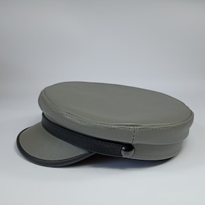 May include: A grey leather cap with a black band and a button on the side.