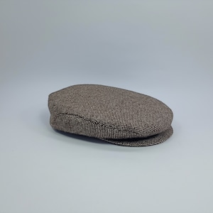 May include: A brown and white patterned tweed newsboy cap.