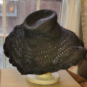 May include: A black wide-brimmed straw hat with a crocheted design around the brim.