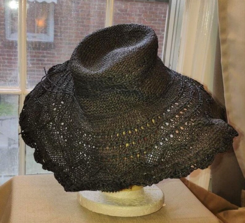 May include: A black wide-brimmed straw hat with a crocheted design around the brim.