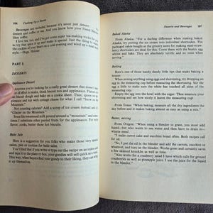 May include: Open book with text about desserts and beverages, including recipes for applesauce dessert and baked Alaska. The pages are yellowed with age, suggesting a vintage cookbook.