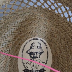 Peut inclure: Un chapeau de paille avec un motif tiss&eacute; brun et une &eacute;tiquette qui indique "Jack Est. 1974 Medium Made in the USA with Love, Care & Pride". Le chapeau a &eacute;galement une &eacute;tiquette avec un dessin d'un homme portant un chapeau et le texte "ORIGINAL Panama Jack".