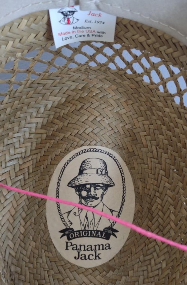 Peut inclure: Un chapeau de paille avec un motif tiss&eacute; brun et une &eacute;tiquette qui indique "Jack Est. 1974 Medium Made in the USA with Love, Care & Pride". Le chapeau a &eacute;galement une &eacute;tiquette avec un dessin d'un homme portant un chapeau et le texte "ORIGINAL Panama Jack".