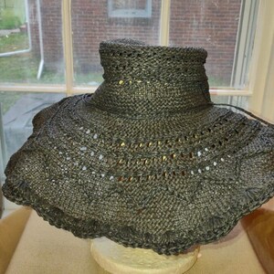 May include: A black wide-brimmed sun hat with a crocheted design. The hat has a wide brim and a high crown.