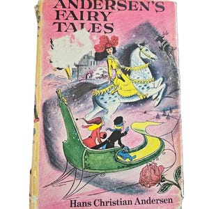 May include: A vintage book cover with a pink background and the title "Andersen's Fairy Tales" in black text. The cover features an illustration of a woman riding a white horse with a yellow and blue saddle, a green sleigh with two people inside, and a pink rose.