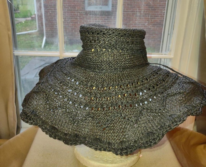 May include: A black wide-brimmed sun hat with a crocheted design. The hat has a wide brim and a high crown.