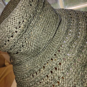 May include: A close-up of a black woven straw hat with a wide brim. The hat is made of a fine, intricate weave.
