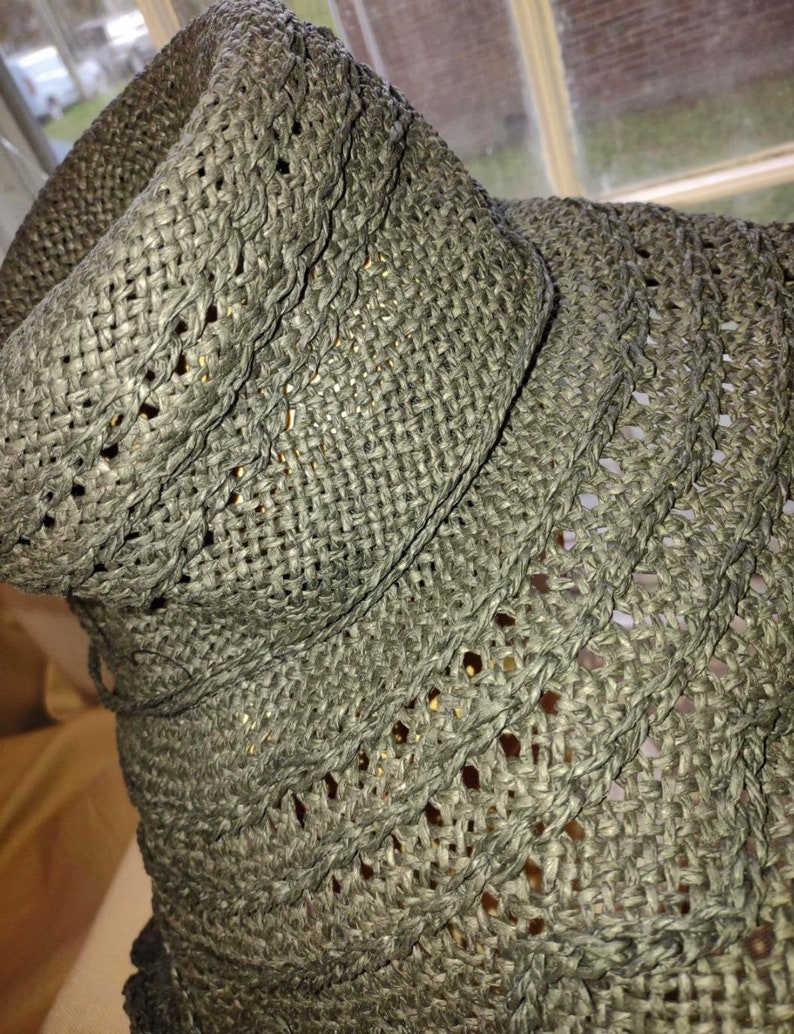 May include: A close-up of a black woven straw hat with a wide brim. The hat is made of a fine, intricate weave.