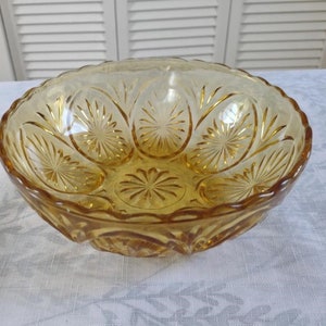 May include: A clear amber glass bowl with a scalloped rim and a starburst pattern.
