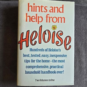 May include: A hardcover book titled "hints and help from Heloise." The cover is white with red and orange text. The book promises hundreds of household tips. The book is a two-volume set.