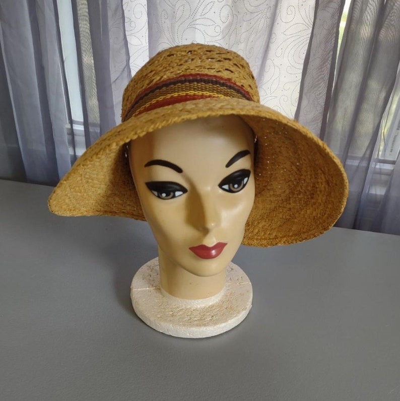 Puede incluir: Un sombrero de paja marr&oacute;n con un dise&ntilde;o tejido y una banda multicolor alrededor de la corona.
