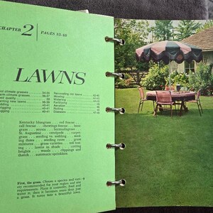 May include: Open book with a green cover and pages. The left page has the title "LAWNS" and a table of contents. The right page shows a color photo of a backyard with a table, chairs, and an umbrella.