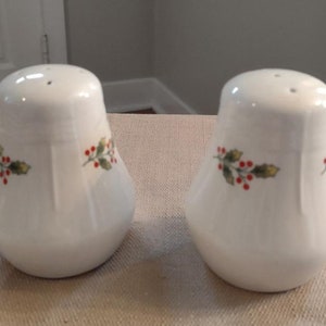 May include: Two white ceramic salt and pepper shakers with a holly and berry design.
