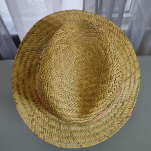 Peut inclure: Un chapeau de paille avec une texture tiss&eacute;e et un ruban rose autour du bord.