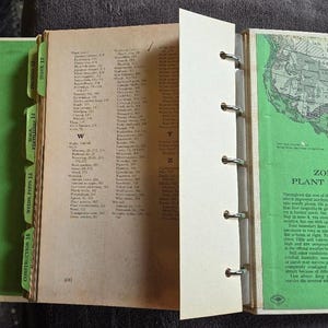 May include: An open vintage book with a green cover and tabs. The pages are filled with text and a map of the United States. The book is bound with metal rings. The tabs read: Construction 16, Weeds, Pests 15, Soils, Fertilizers 14, and Index 17.