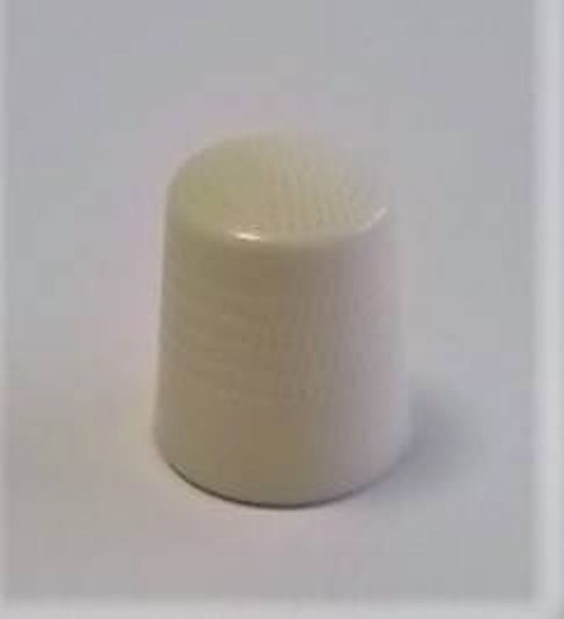 May include: A white ceramic thimble with a textured surface.