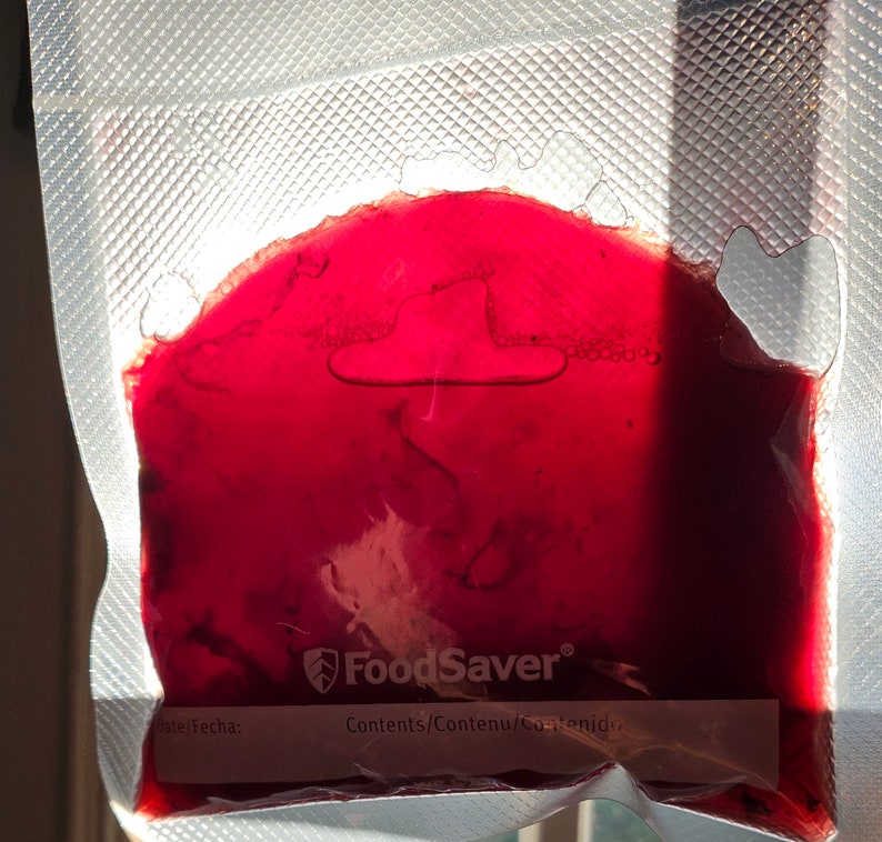 May include: A red liquid is inside a clear plastic bag with the FoodSaver logo and the words "Contents/Contenu/Contenido".