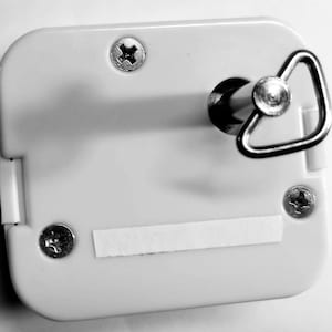 May include: A white music box with a silver winding key and a small piece of tape on the front.
