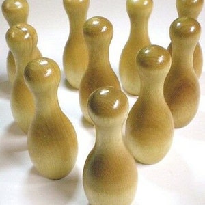 May include: A set of ten wooden bowling pins in a light brown color. The pins are arranged in a triangle shape on a white surface.