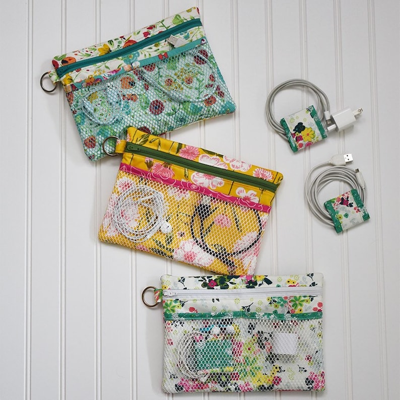 May include: Three floral print zippered pouches with mesh pockets, and two matching cable organizers. The pouches are in shades of yellow, teal, and white, with a variety of floral patterns. Each pouch has a metal ring attached.
