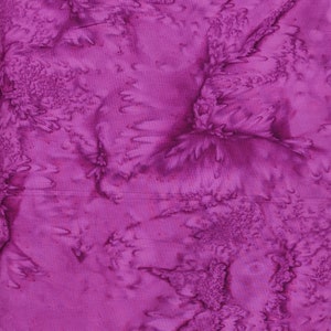 May include: A close-up of a vibrant, textured fabric in shades of magenta and purple. The fabric has a batik-like appearance with swirling patterns and a slightly raised, tactile surface. The design features organic, flowing shapes.