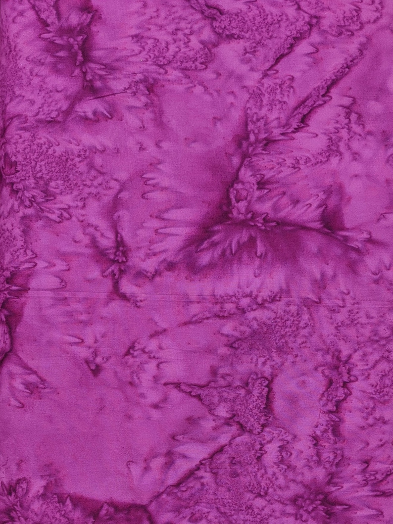 May include: A close-up of a vibrant, textured fabric in shades of magenta and purple. The fabric has a batik-like appearance with swirling patterns and a slightly raised, tactile surface. The design features organic, flowing shapes.